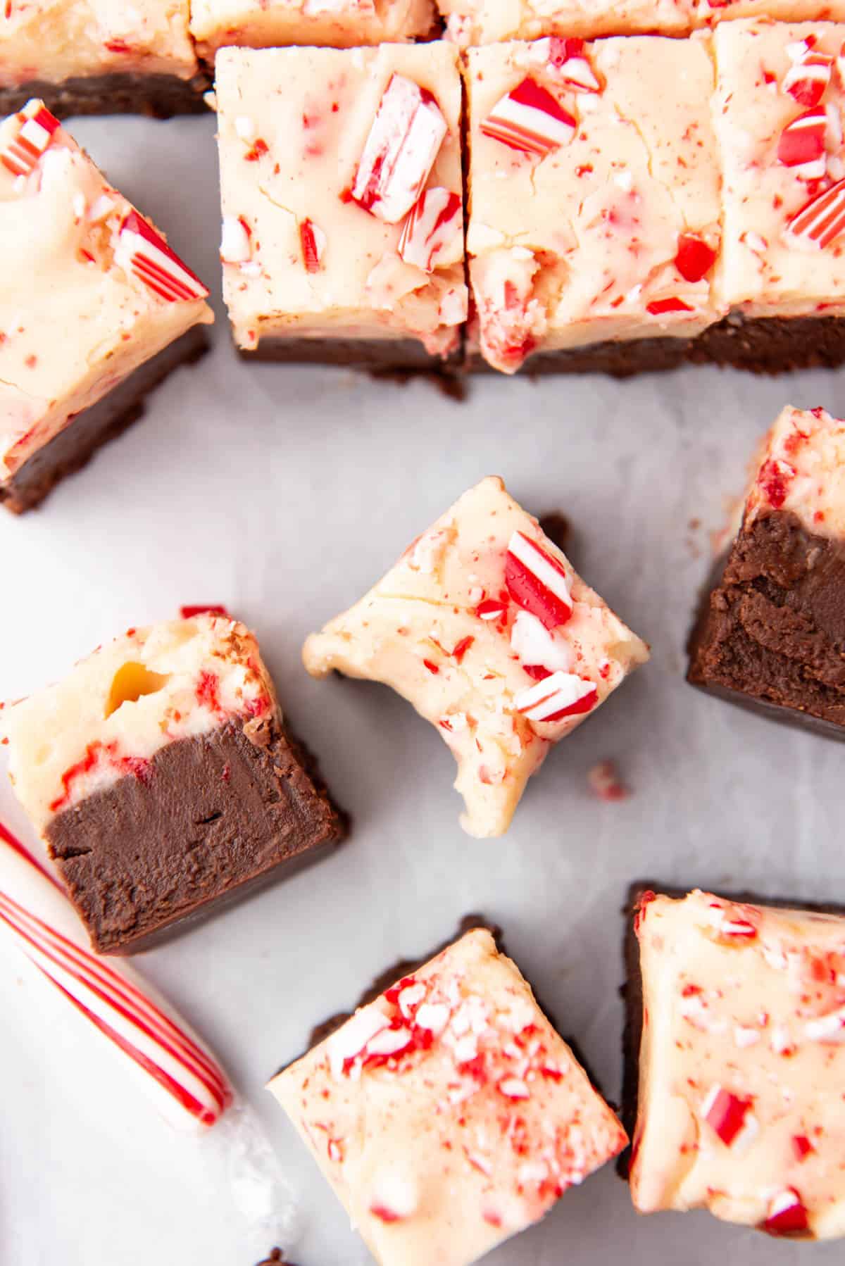 An overhead image of pieces of peppermint bark fudge with a bite taken out of one of them.