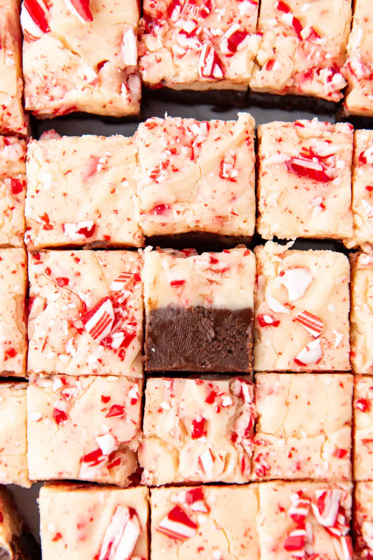 A close image of peppermint bark fudge squares with one turned on its side.