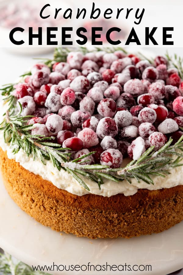 A cranberry cheesecake decorated with sugared cranberries and rosemary with text overlay.