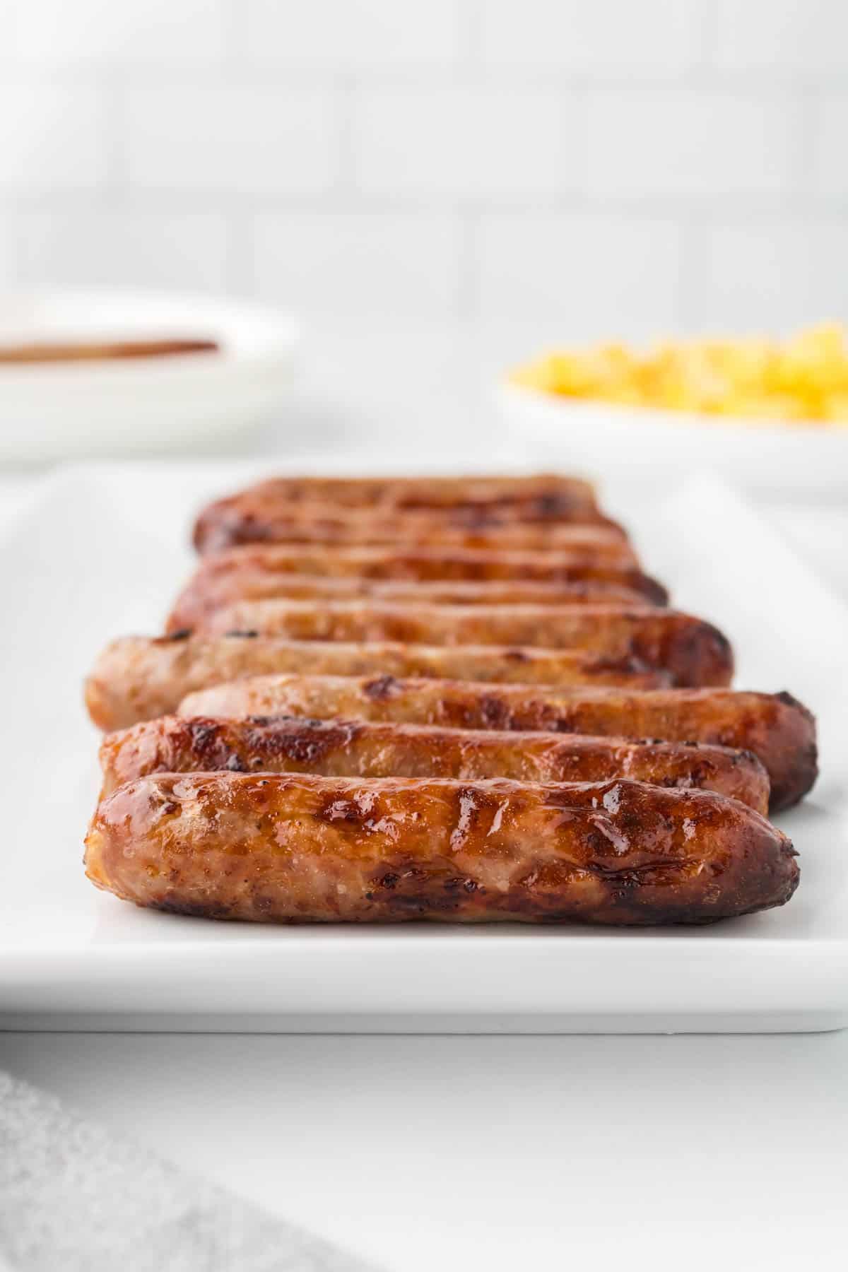 A plate full of cooked breakfast sausage links.