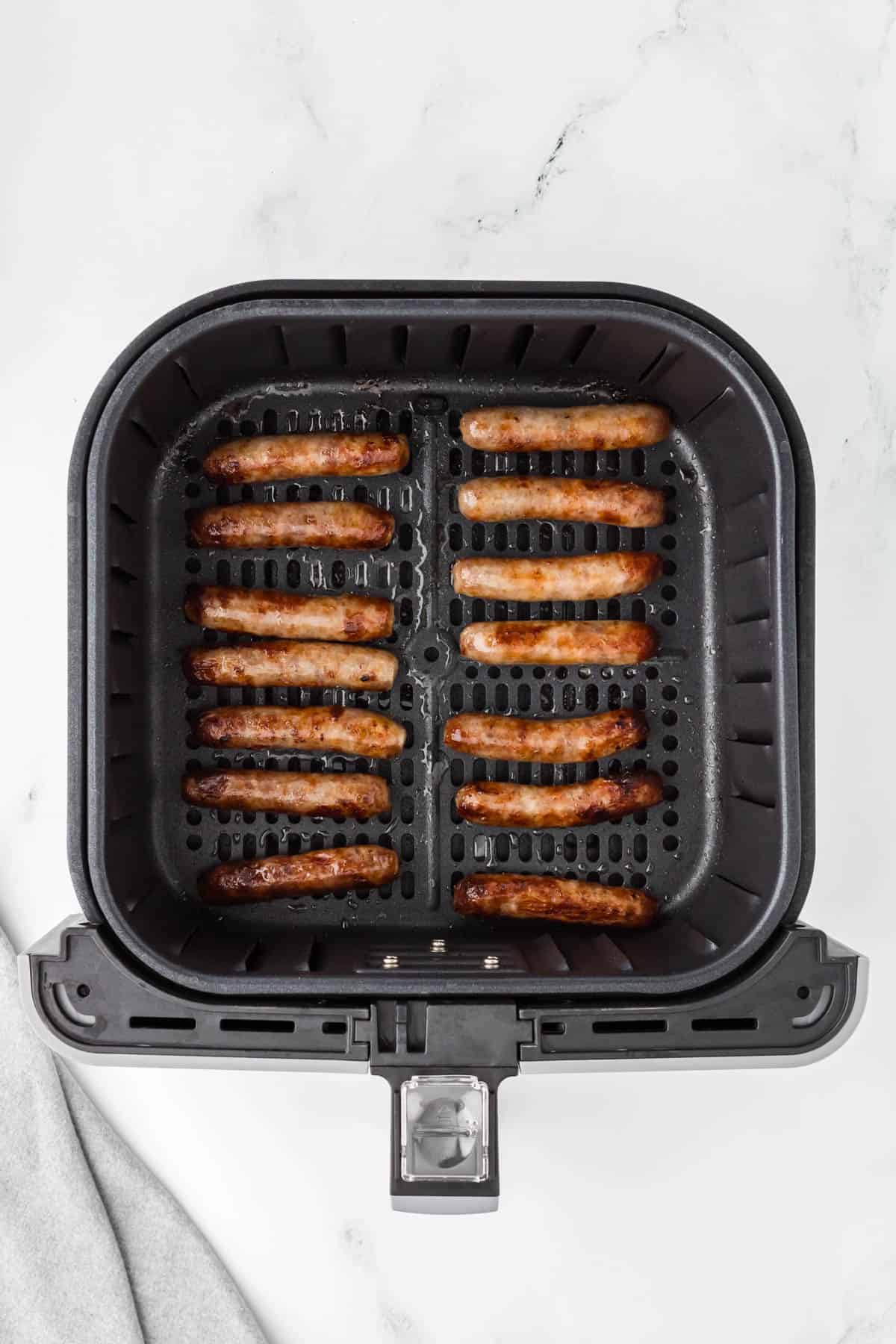 Cooked breakfast sausage links in an air fryer.