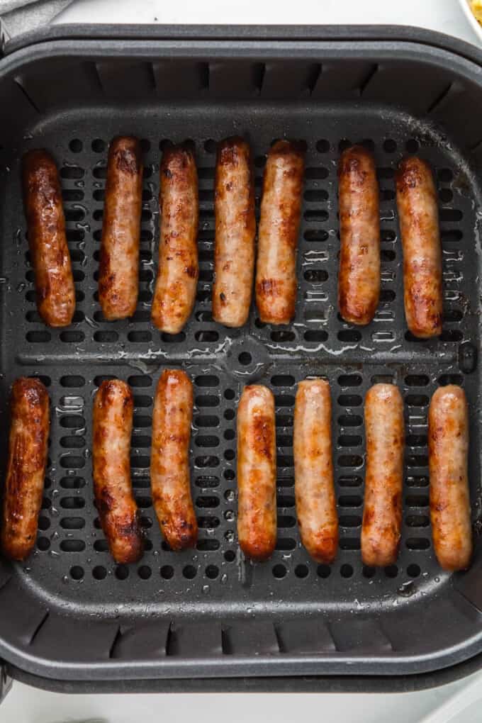 A close image of rows of cooked breakfast sausage links in an air fryer basket.