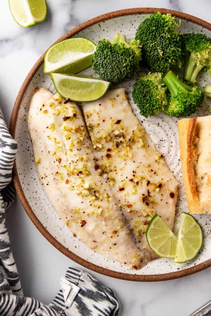 An overhead image of baked tilapia with lime on a plate.