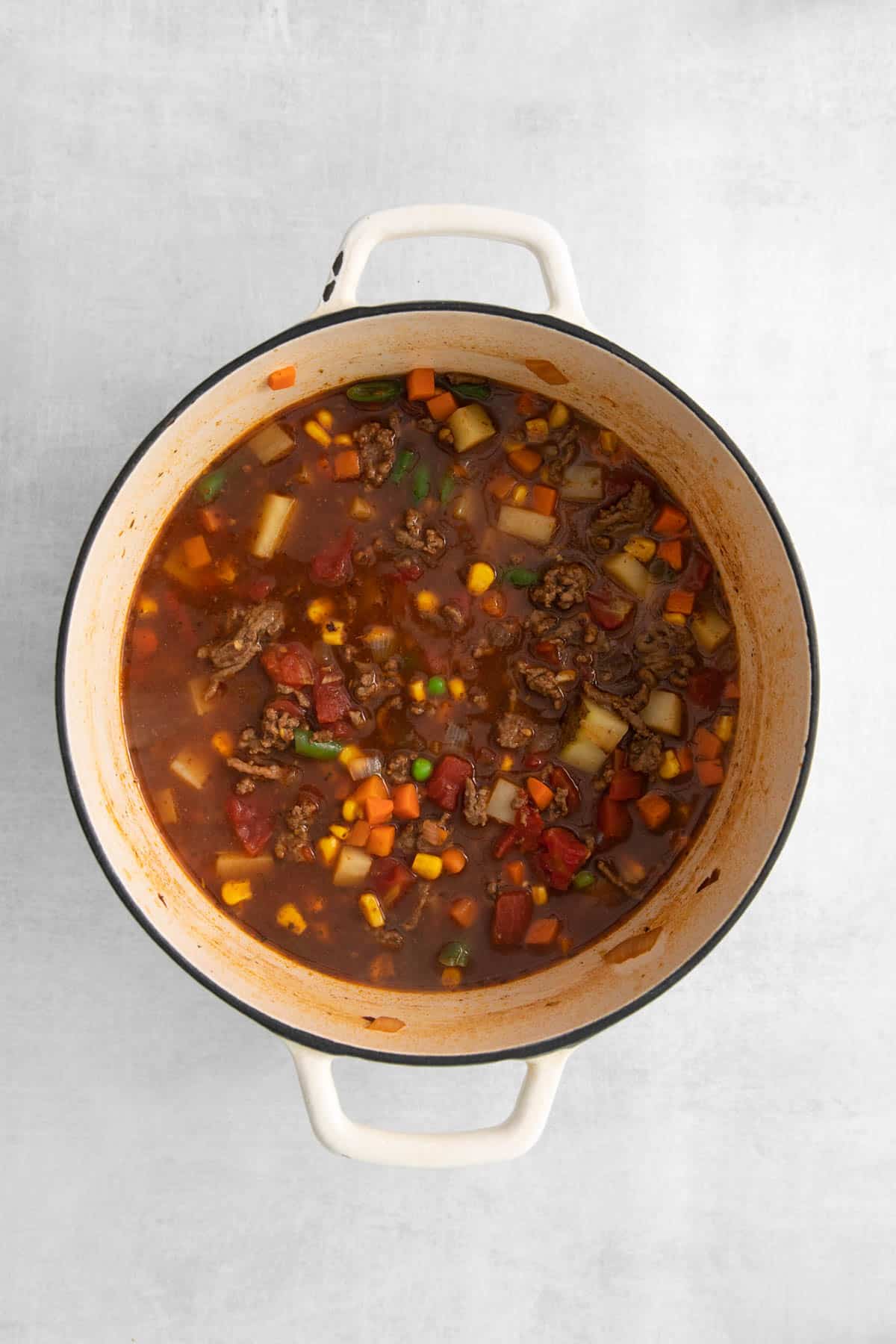 An overhead image of a pot of vegetable beef soup.