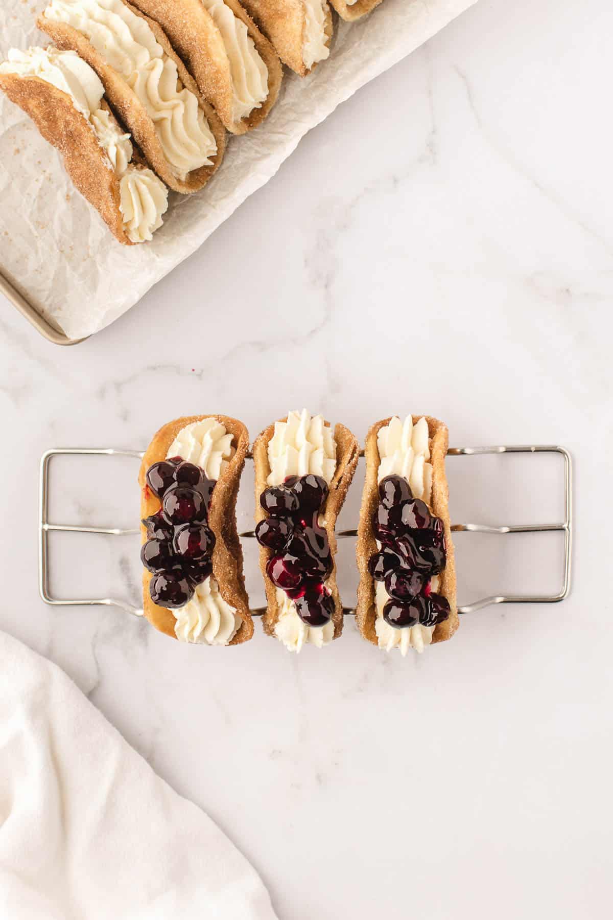 Blueberry pie filling spooned on top of cheesecake filling in dessert tacos.