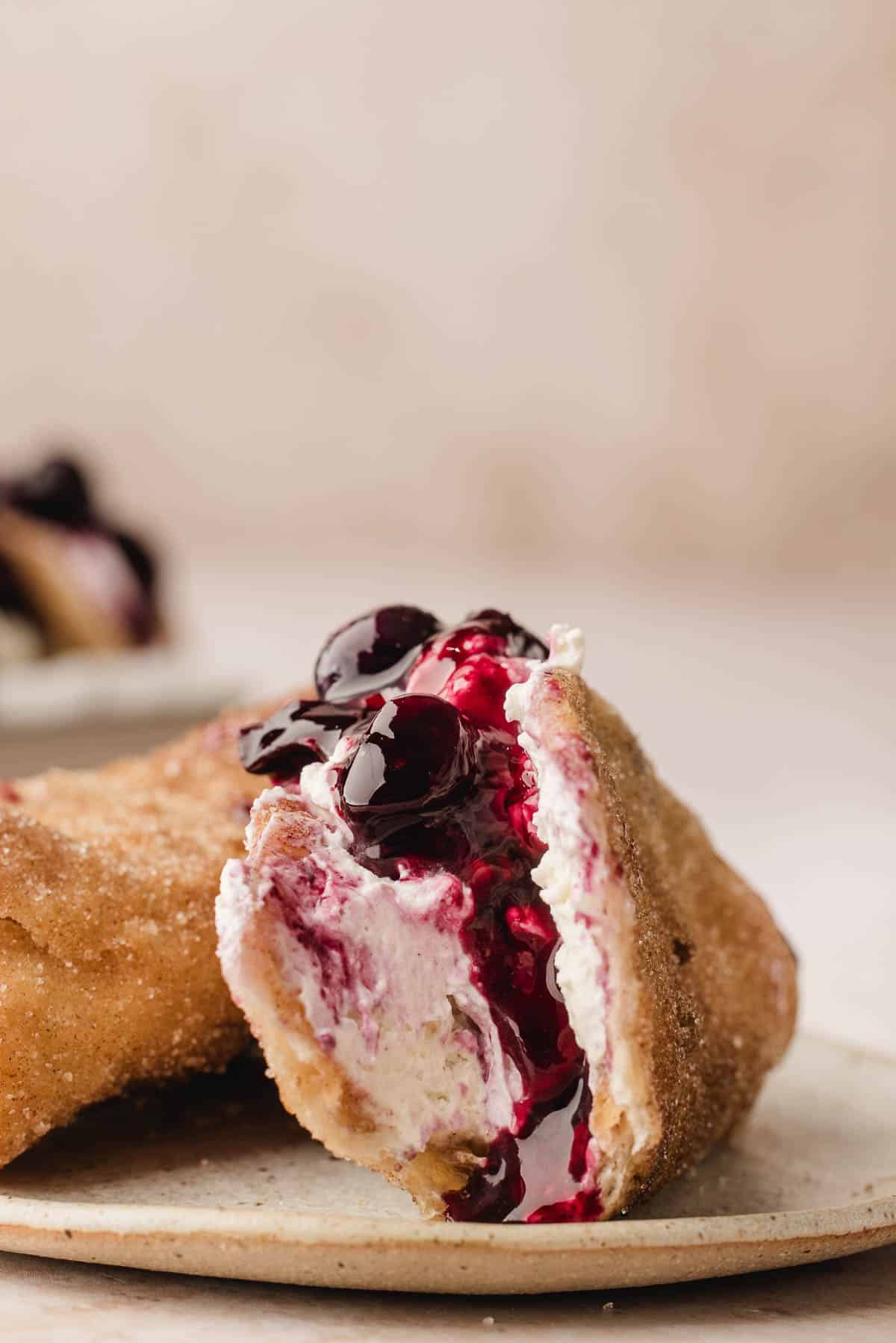 A blueberry cheesecake taco with a bite taken out of it on a plate.
