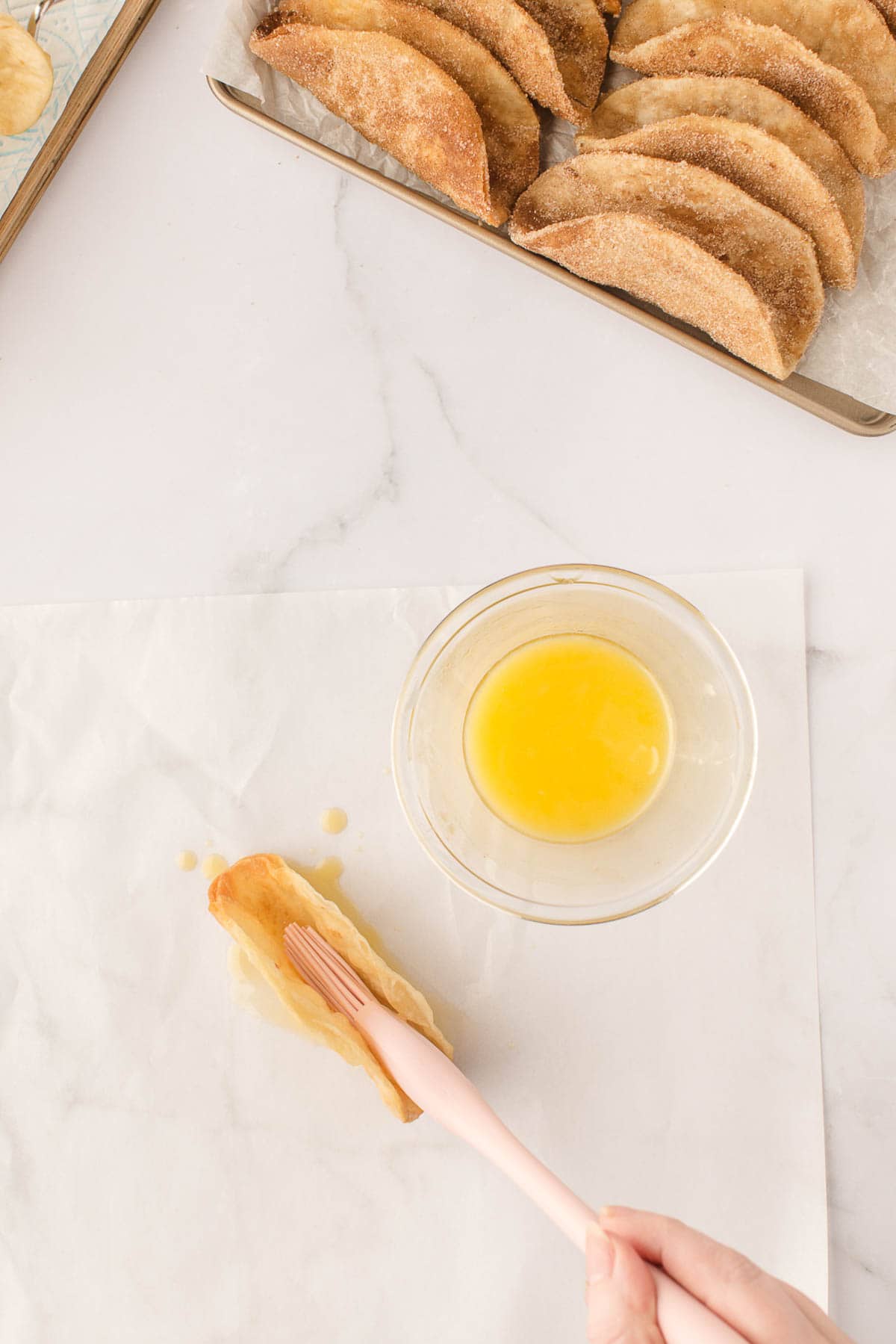 Brushing fried tortilla shells with melted butter.