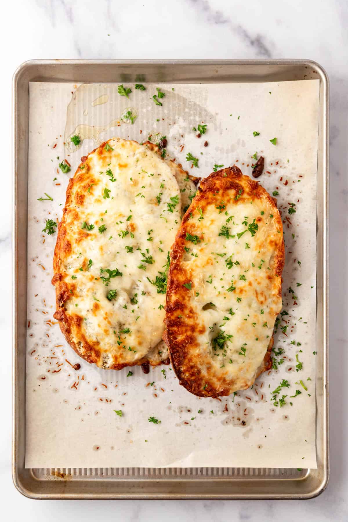 Baked cheesy garlic bread on a baking sheet lined with parchment paper.