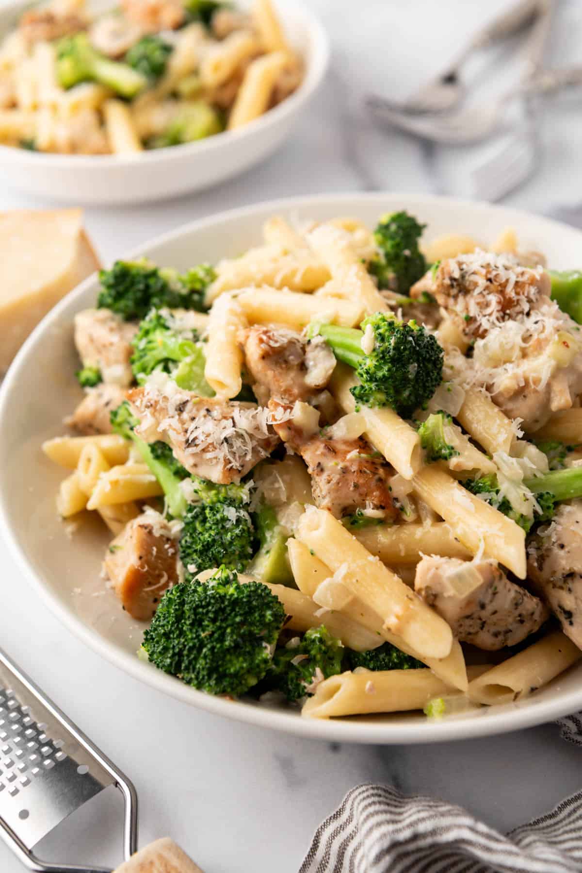 An image of a white pasta bowl filled with chicken broccoli pasta.