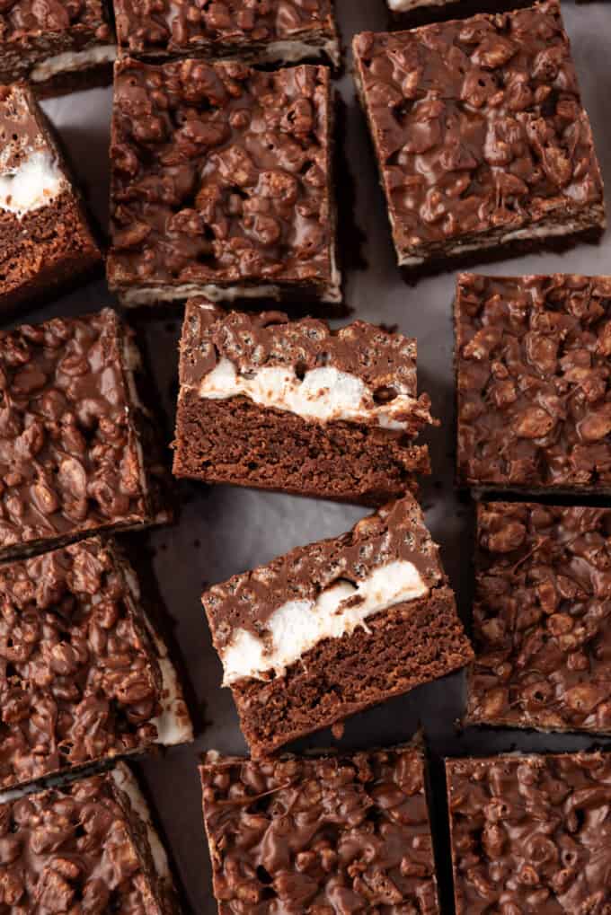 A close up  image of two chocolate peanut butter crunch brownies on their sides showing the middle marshmallow layer.