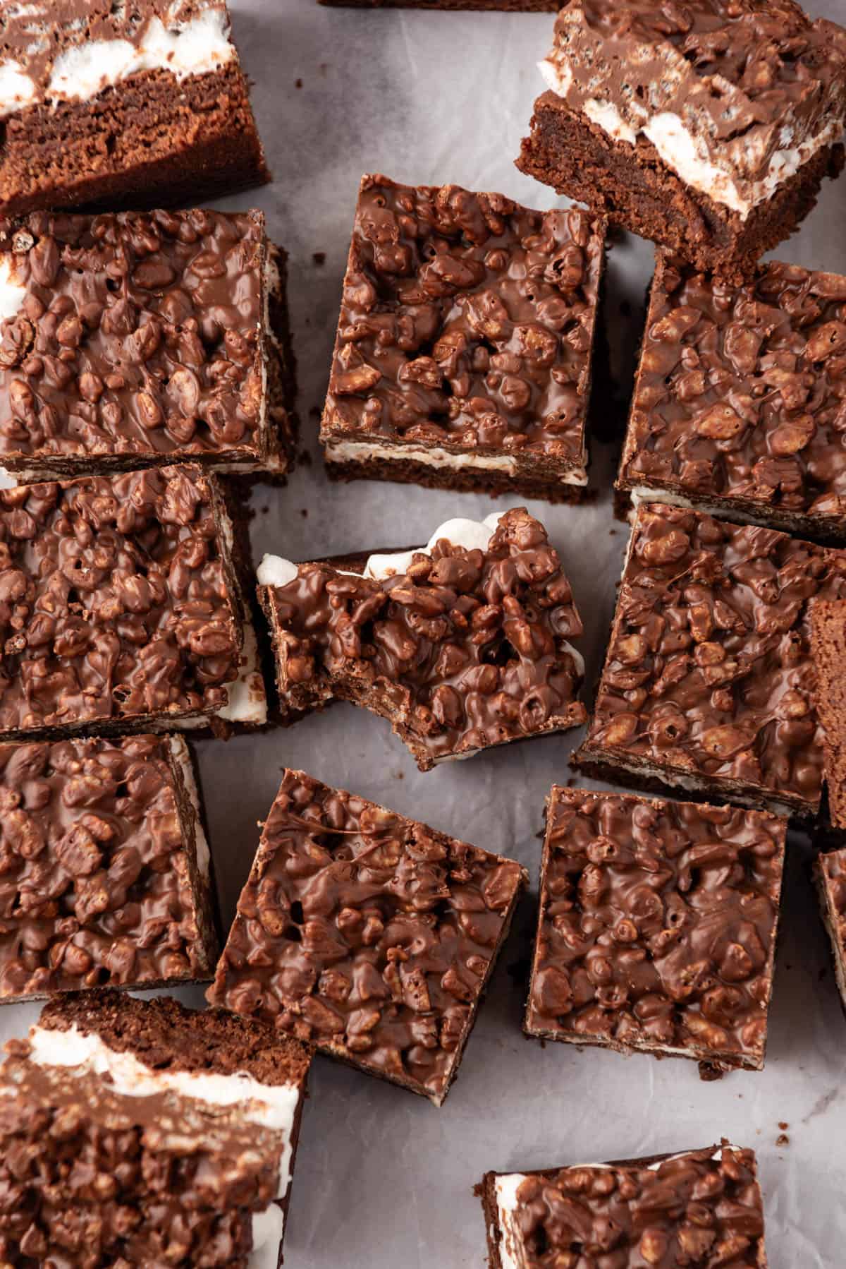 An overhead image of brownies with chocolate rice krispie topping with a bite taken out of one of them.