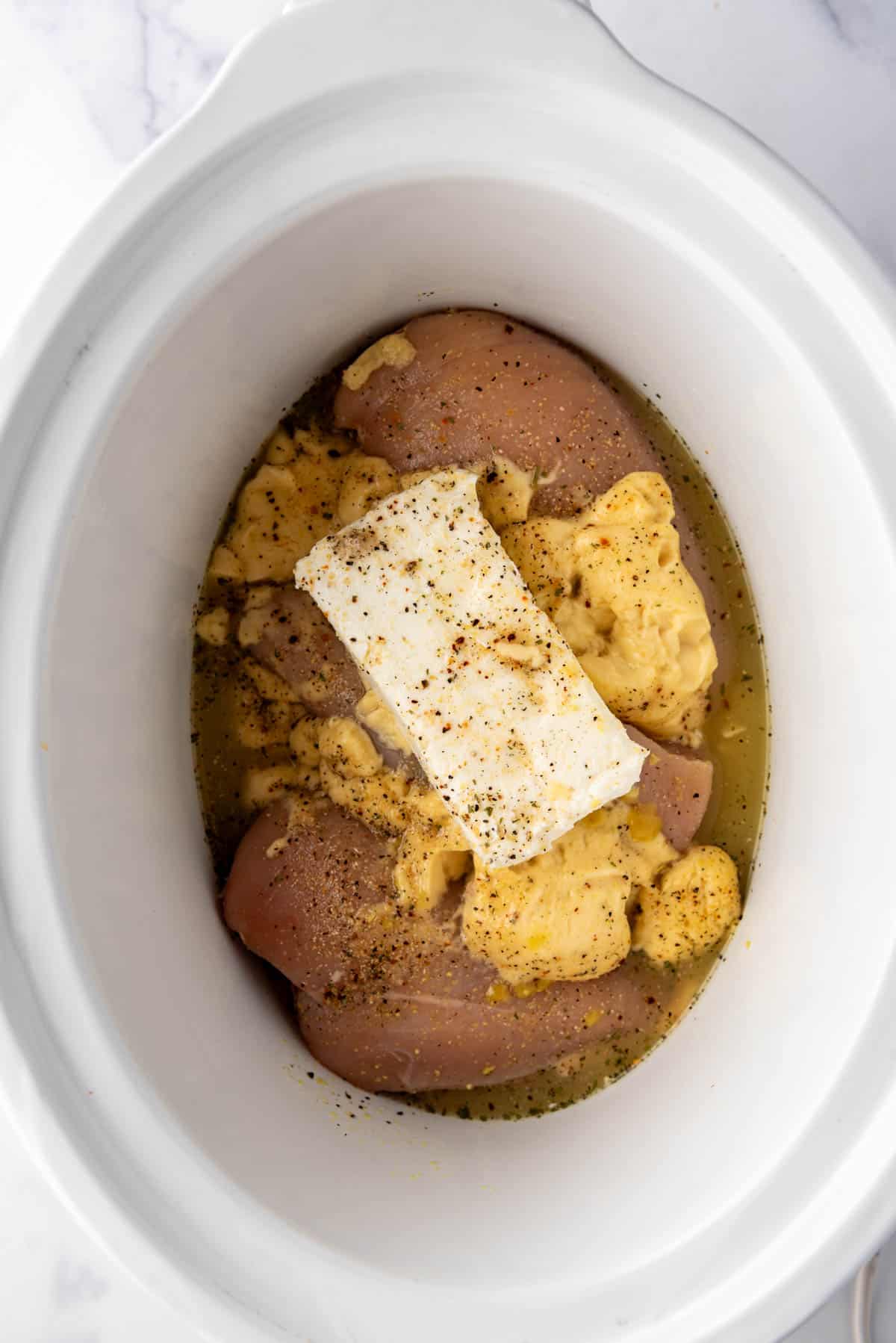 An overhead image of ingredients in a white crockpot.