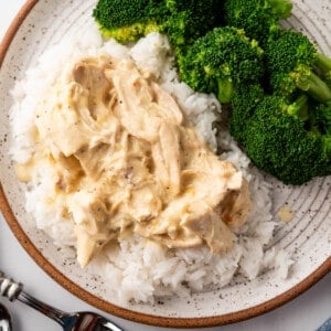 An overhead image of a plate of crock pot creamy Italian chicken over rice with broccoli on the side.