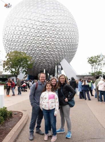 A family in front of the sphere at Epcot at Walt Disney World.