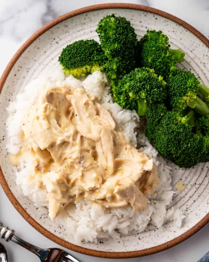 An overhead image of a plate of crock pot creamy Italian chicken over rice with broccoli on the side.