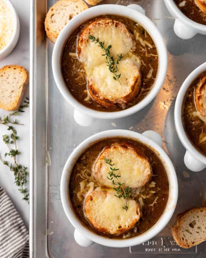 An overhead image of bowls of French onion soup on a baking sheet.