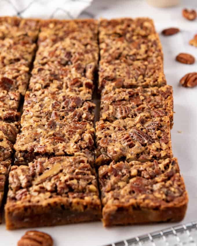 Pecan pie bars sliced into squares with a metal cooling rack in front of them.