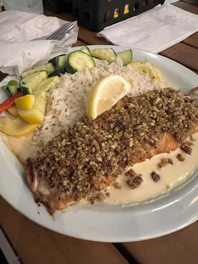 Pecan crusted salmon on a plate with rice and vegetables.
