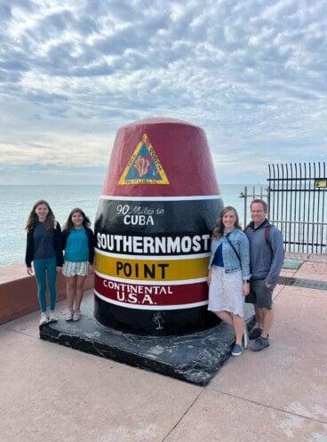 An image of a family in front of the southernmost point of the continental United States marker in Key West, Florida.