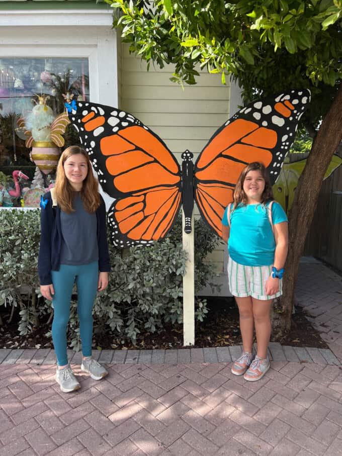 Two girls in front of a painted butterfly sign.