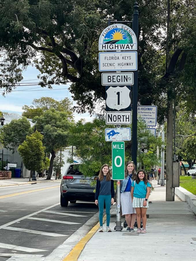 A mom and two kids in front of the Florida Highway Mile Marker 1 sign.