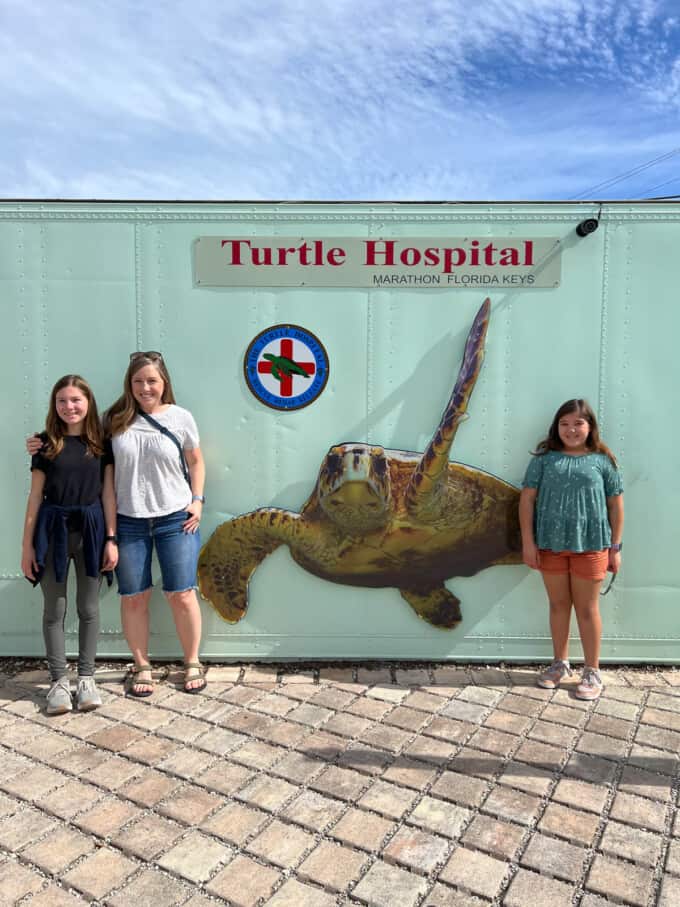 A mom and kids in front of a turtle hospital sign.