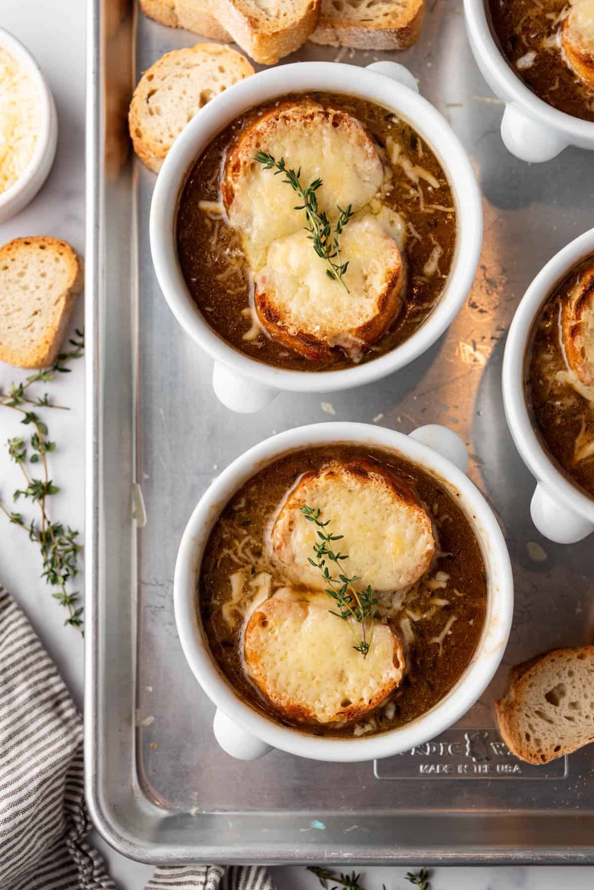 An overhead image of bowls of French onion soup on a baking sheet.