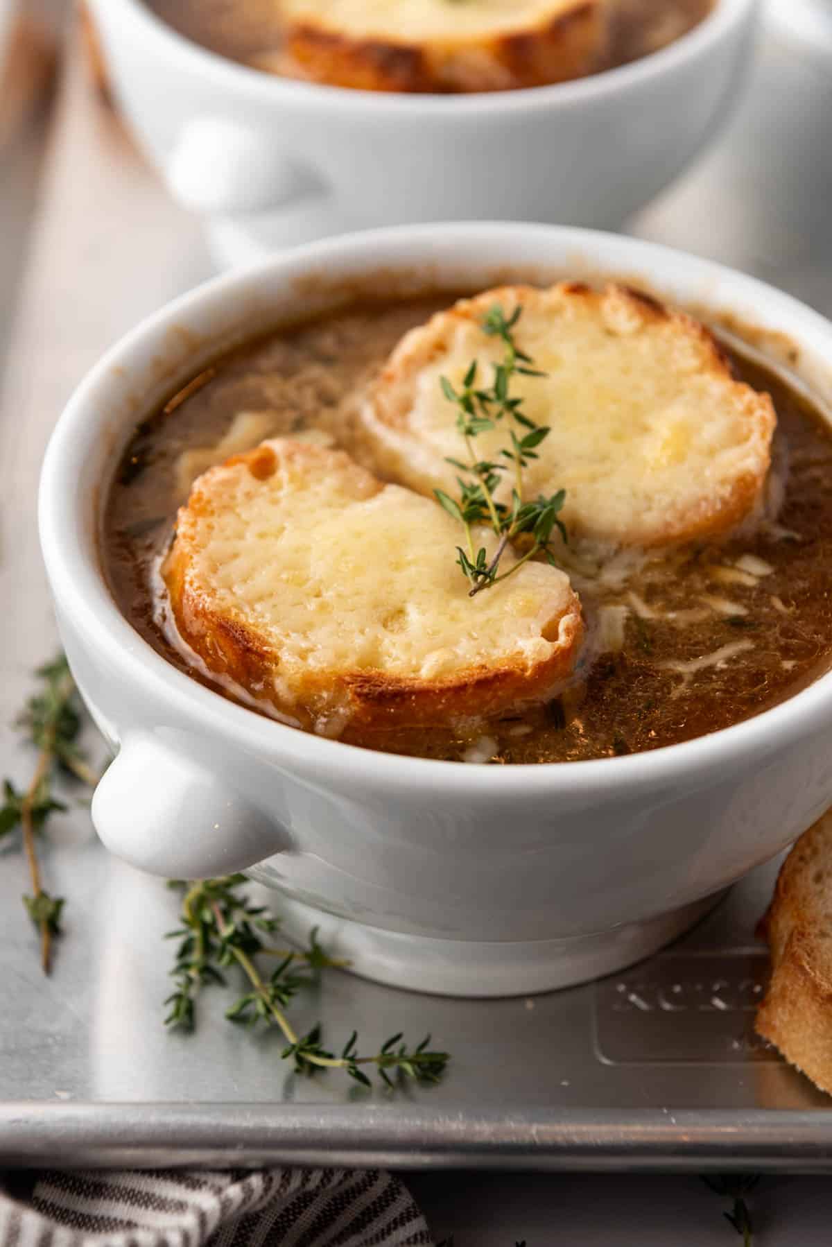 A side view of a white bowl of French onion soup.