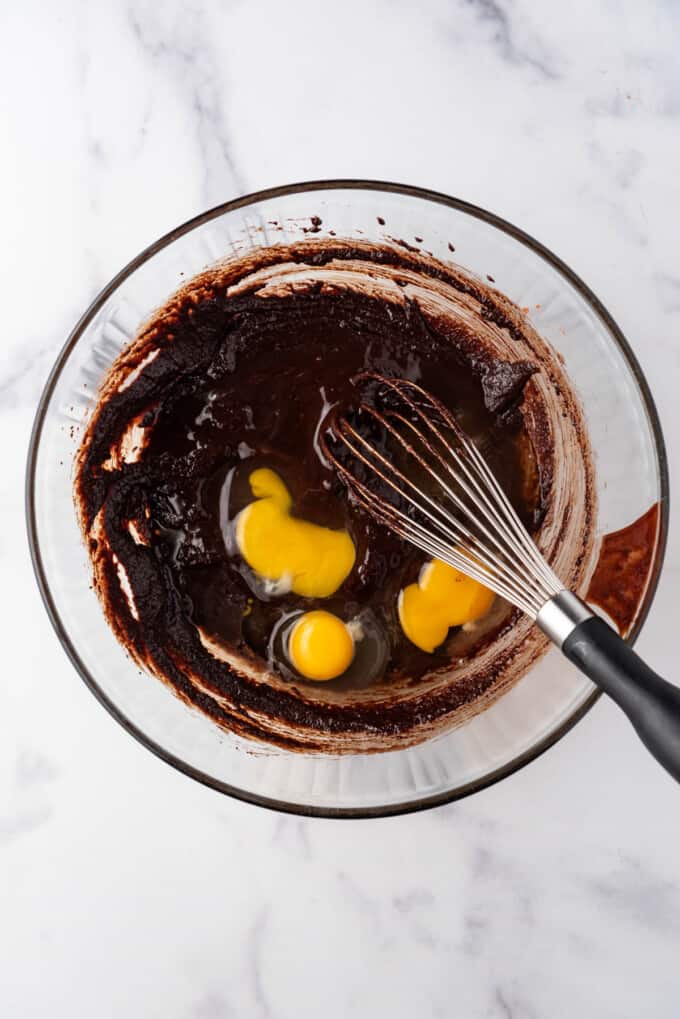 Whisking eggs and vanilla into brownie batter.