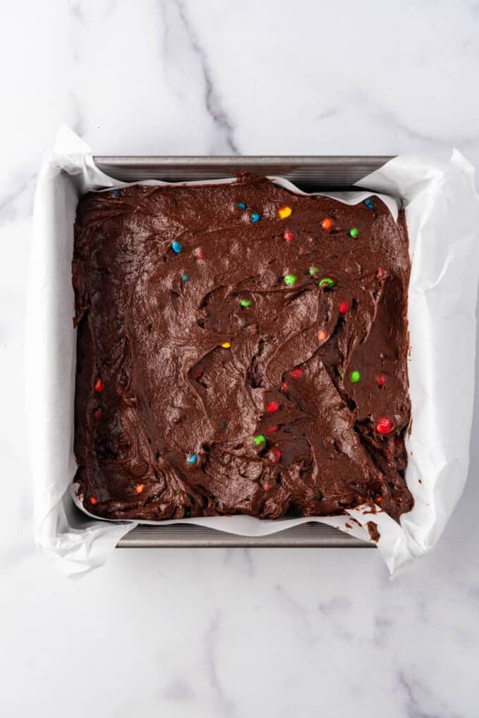 Spreading M&M brownie batter into a square pan.