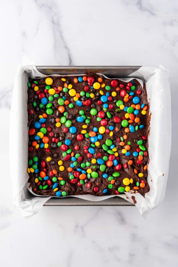 Sprinkled M&M's on top of a pan of brownie batter before baking.