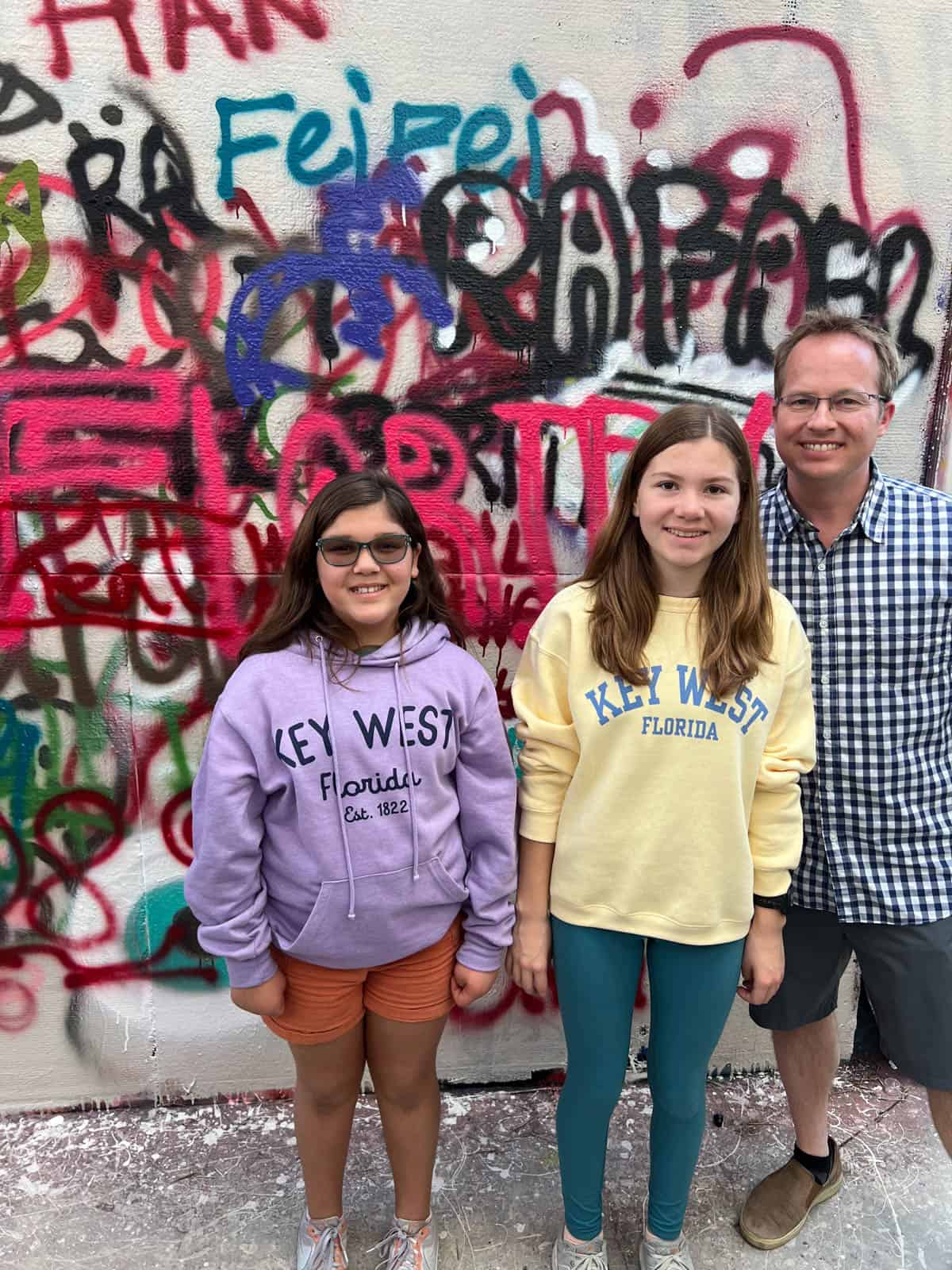 A dad and two daughters in front of graffiti at Wynwood Walls in Miami.