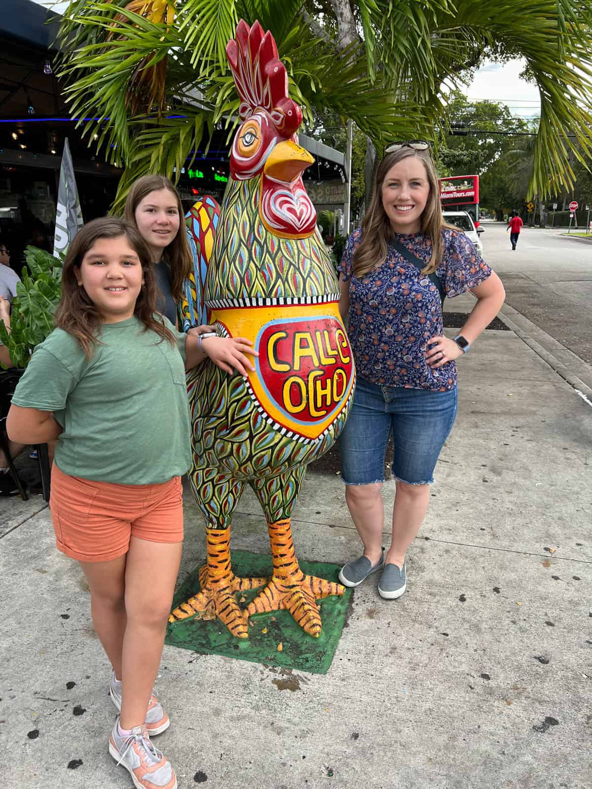 An image of a mom and kids in front of one of the Calle Ocho roosters in Little Havana, Miami, Florida.