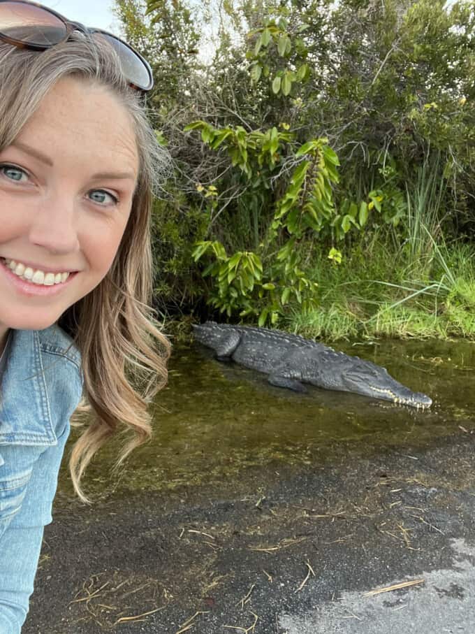 A woman posing in front of a crocodile in Everglades National Park.