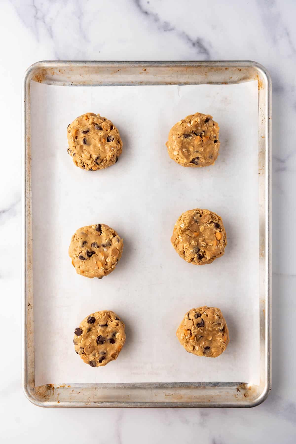 Oatmeal butterscotch cookie dough balls on a baking sheet lined with parchment paper.