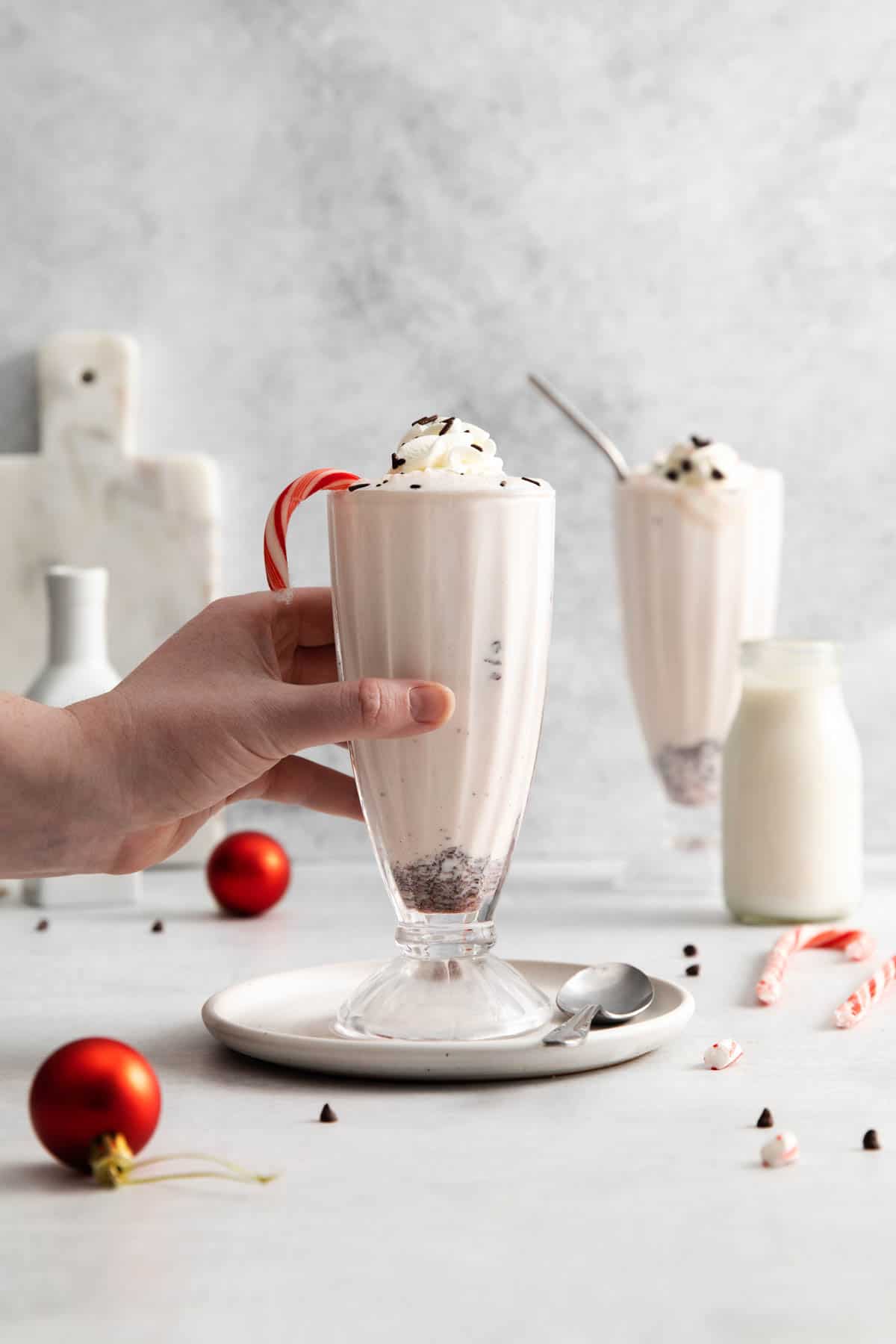 A hand reaching for a peppermint bark milkshake.