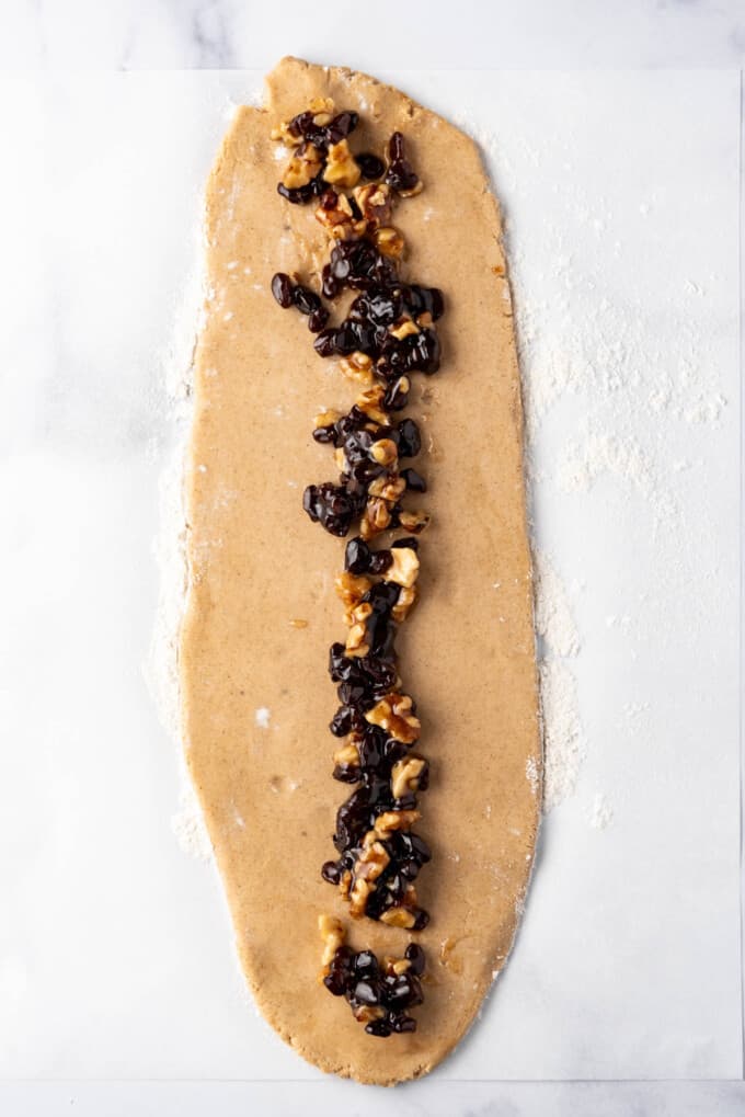 A line of raisin-walnut filling spread down the center of a large rectangle of cookie dough.