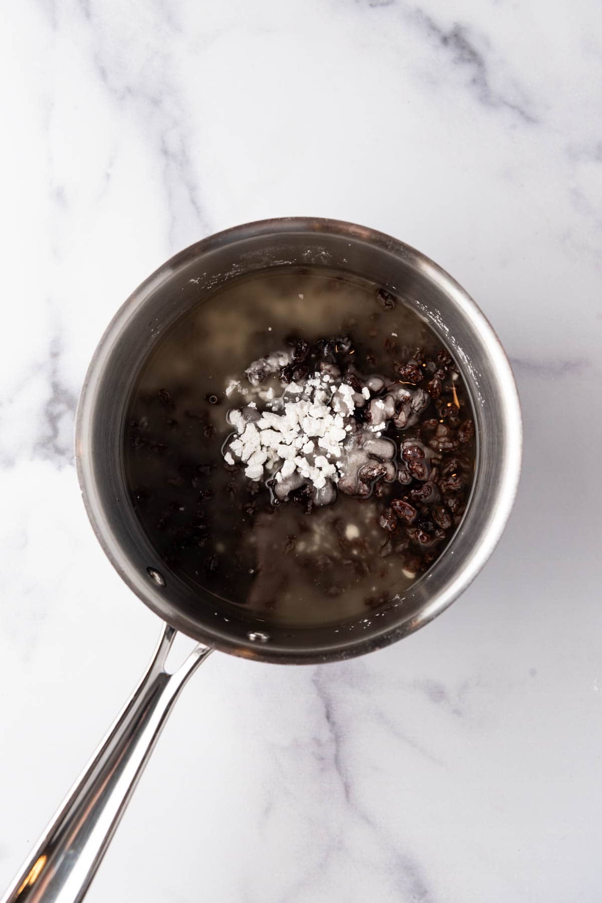 Combining raisins, sugar, and cornstarch in a saucepan.