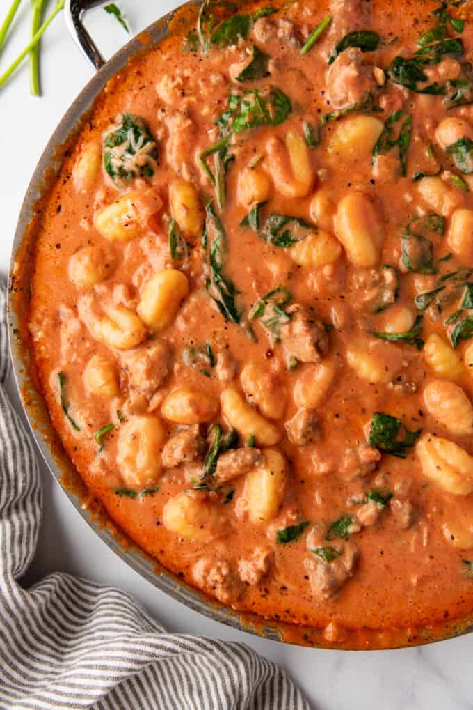 An overhead image of sausage gnocchi in a creamy tomato sauce.