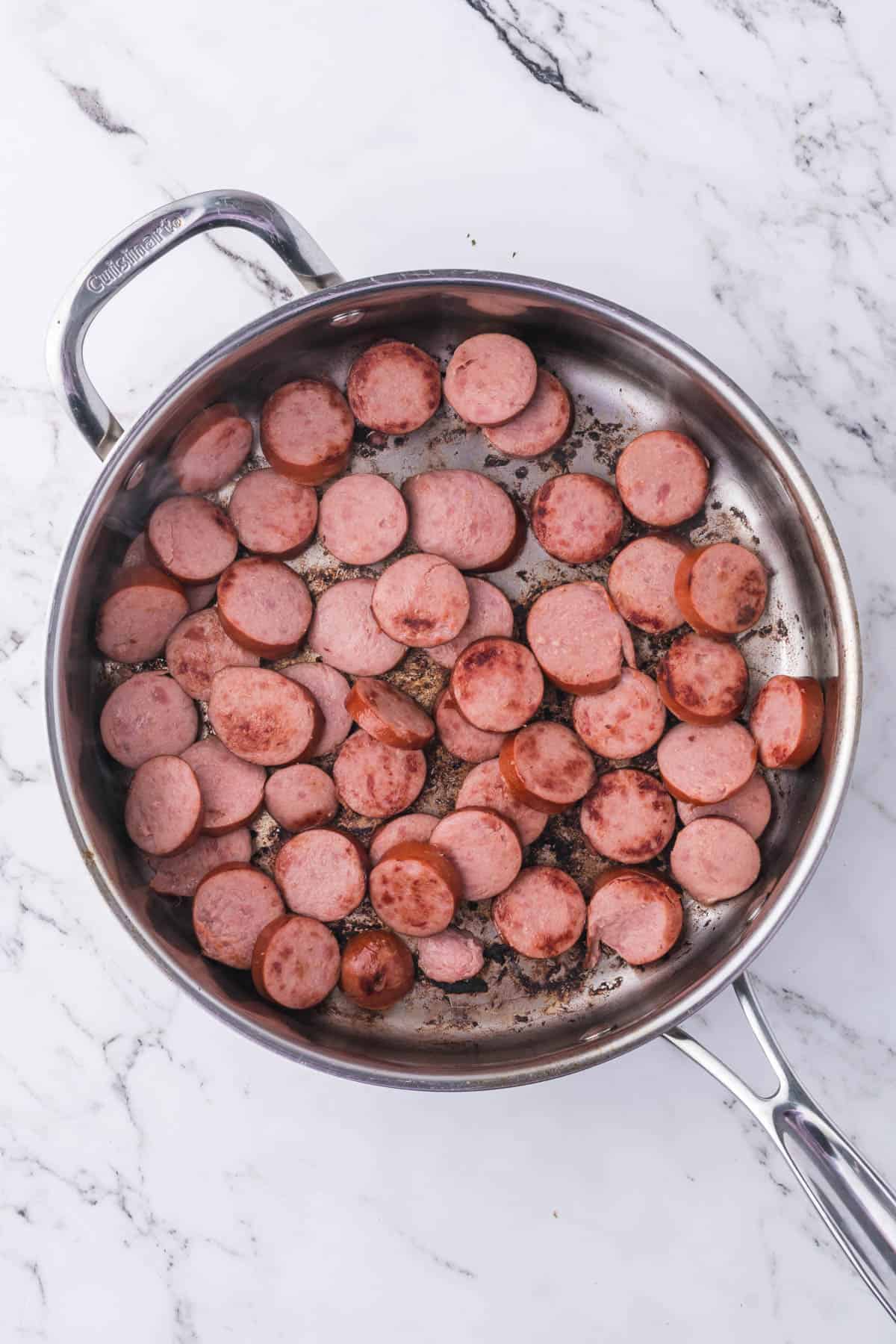 Sauteeing sliced smoked sausage in a pan.