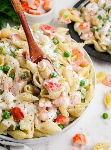 A spoon scooping up some seafood pasta salad.