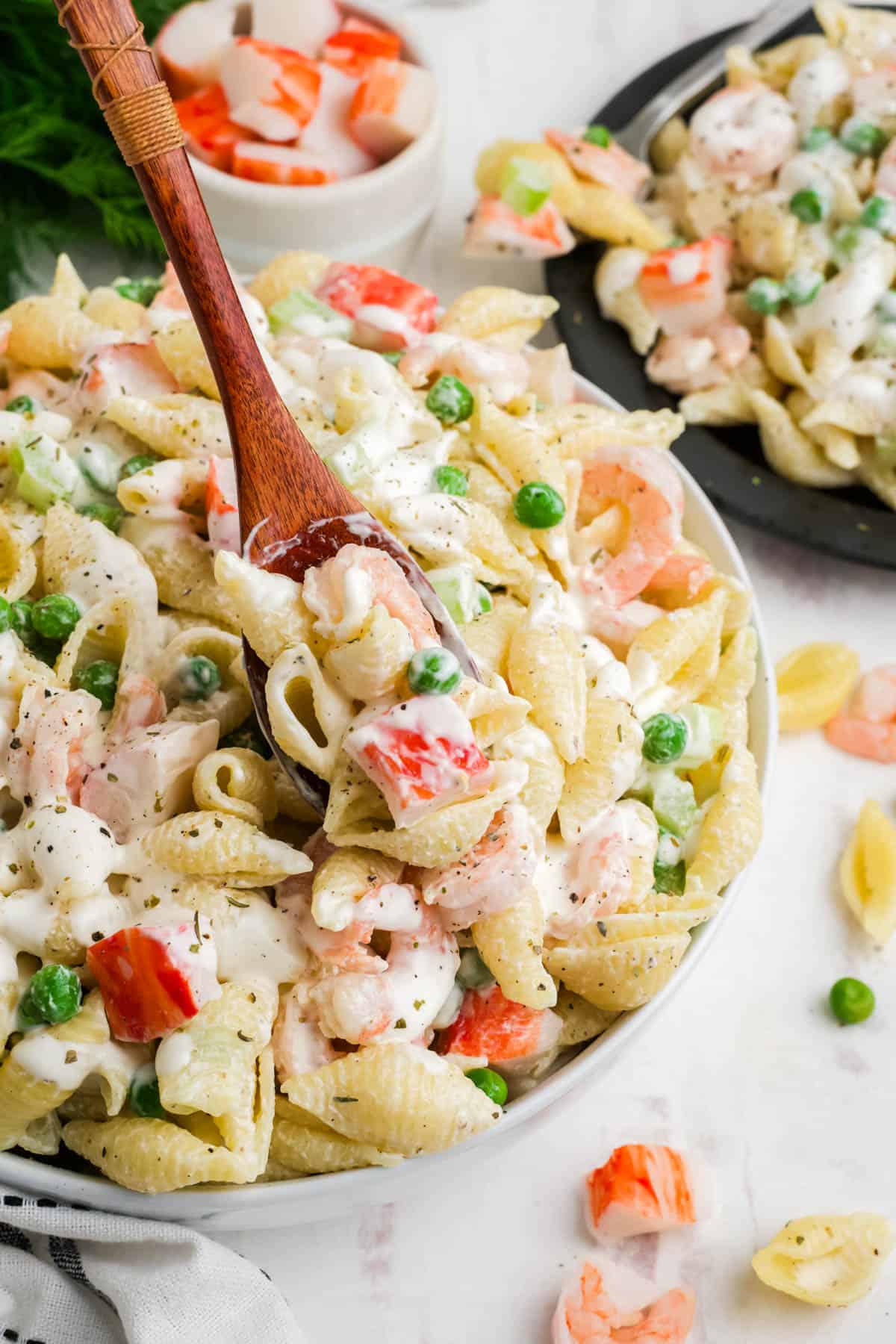 A spoon scooping up some seafood pasta salad.
