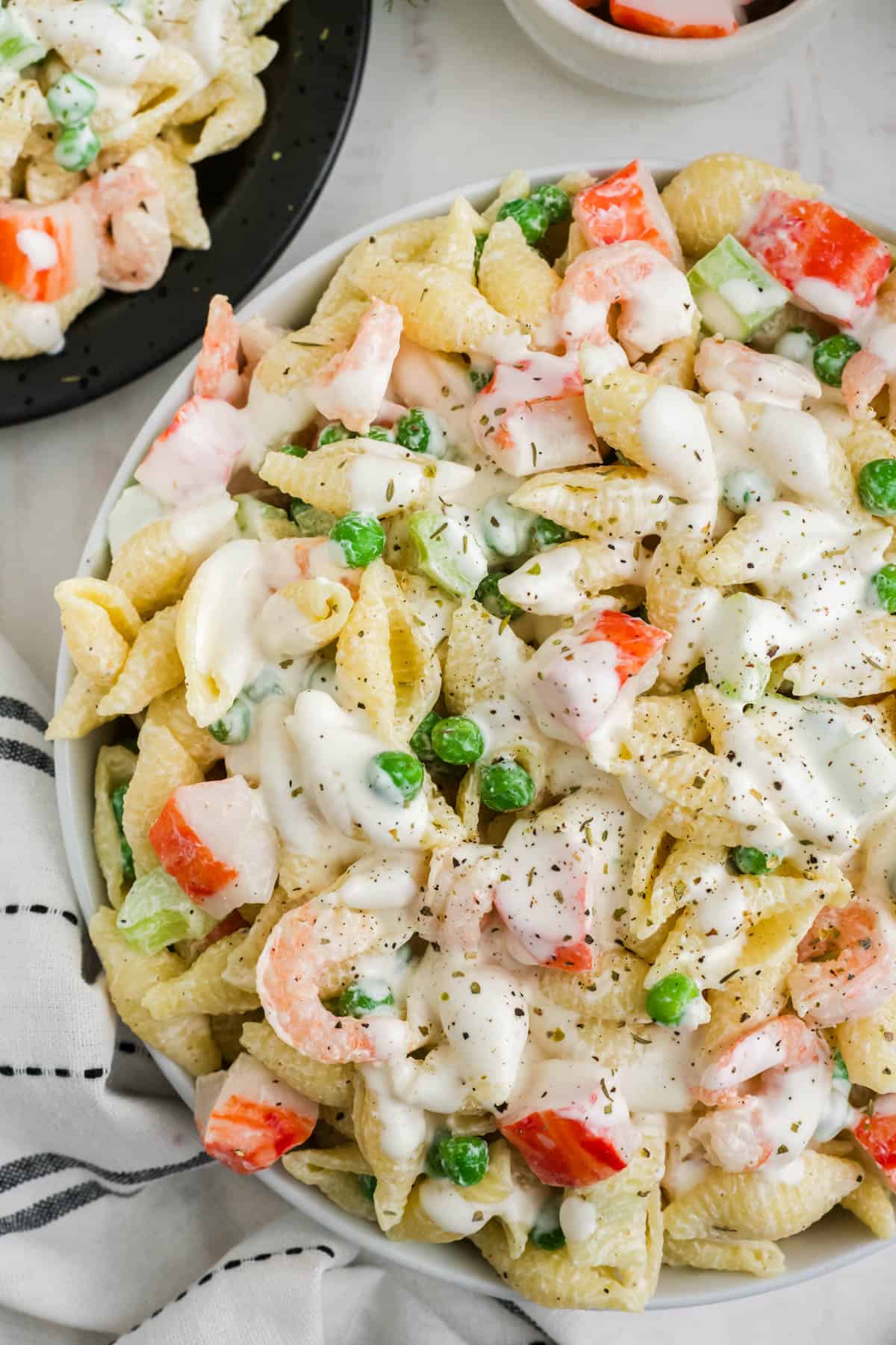 An overhead image of a bowl of shell pasta salad with seafood in a creamy dressing.