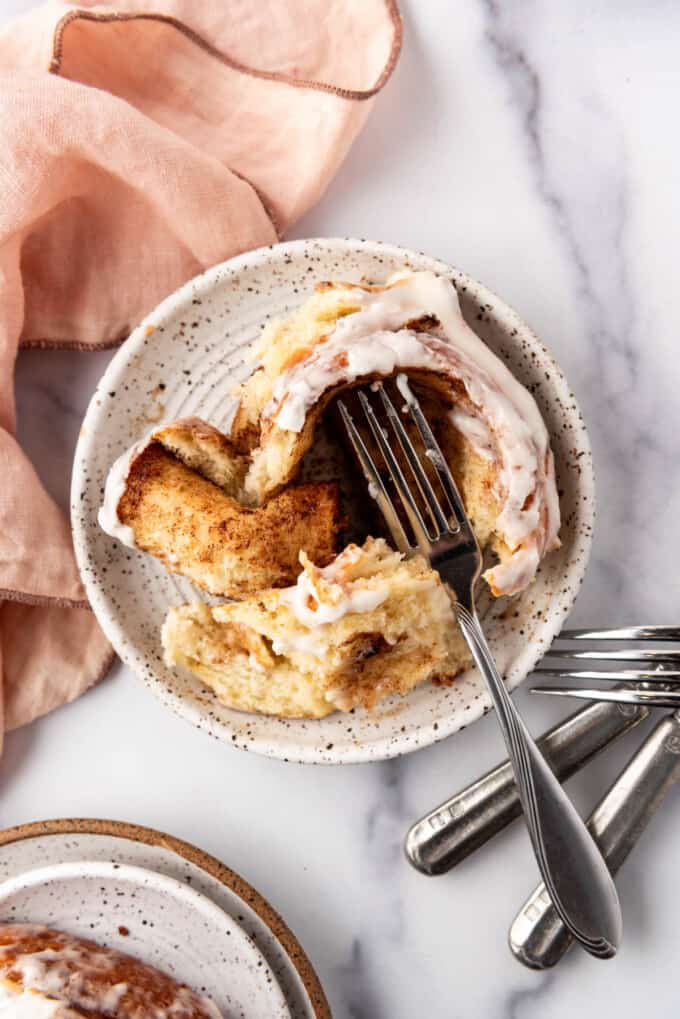 An overhead image of a cinnamon roll on a plate with a fork.