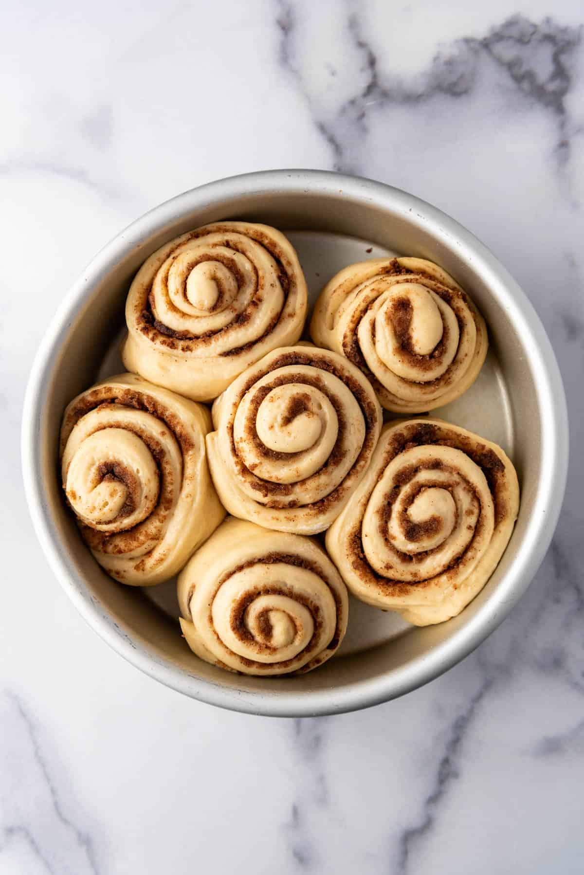 Risen cinnamon rolls in a pan ready to go into the oven.