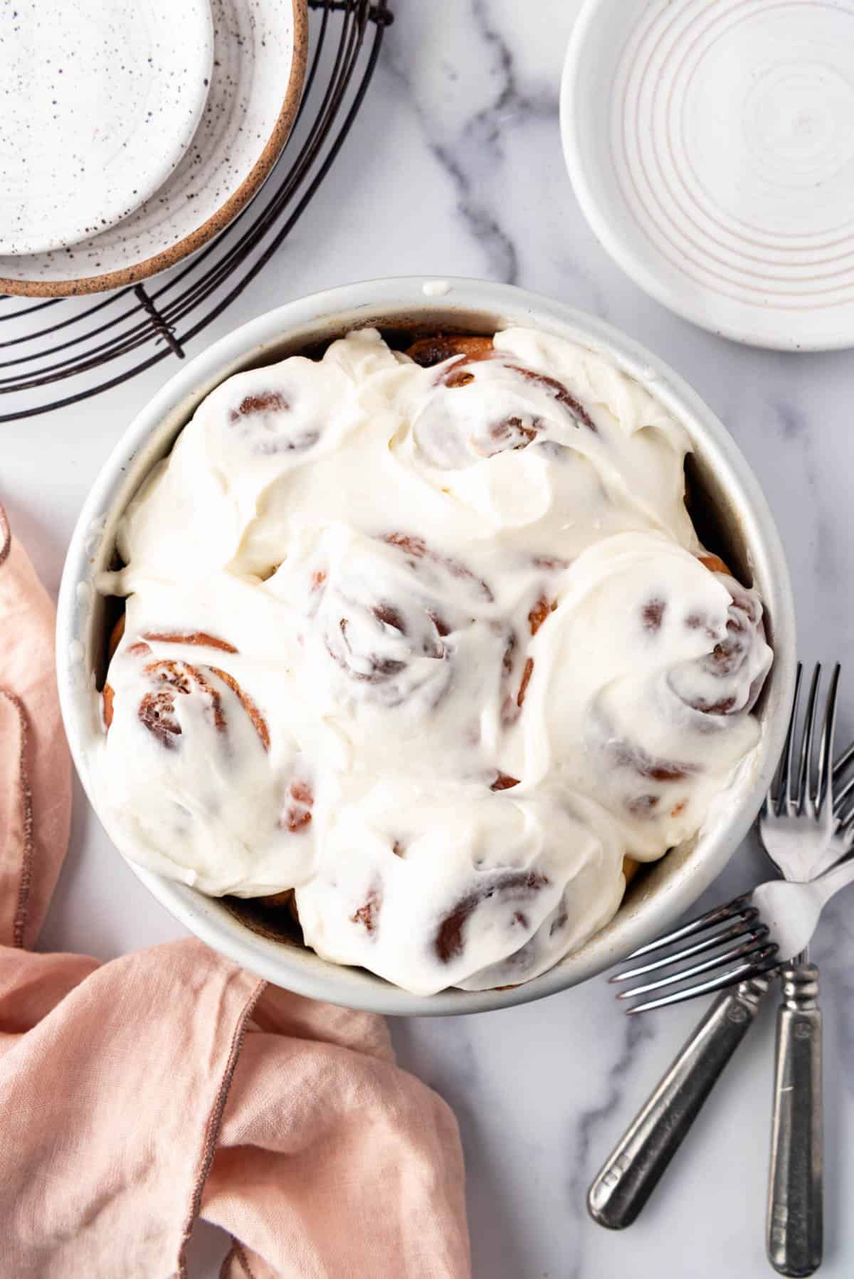 An overhead image of a small batch of cinnamon rolls in a round pan.