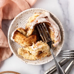 An overhead image of a cinnamon roll on a plate with a fork.