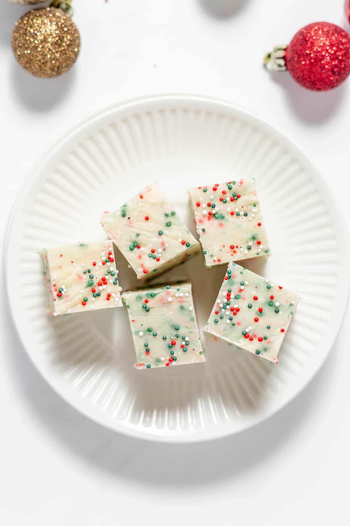 An overhead image of 5 squares of sugar cookie fudge on a plate.