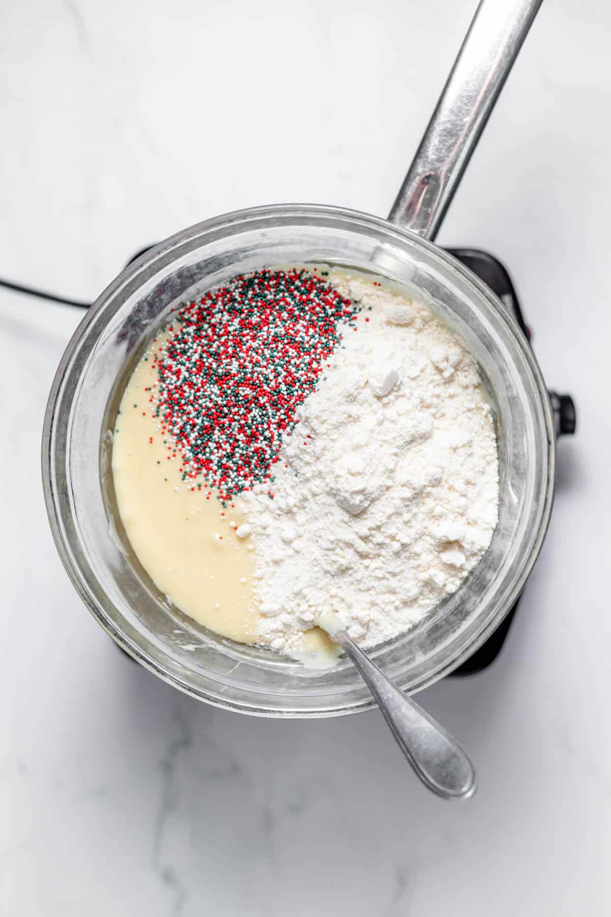 Adding flour and sprinkles to fudge mixture.