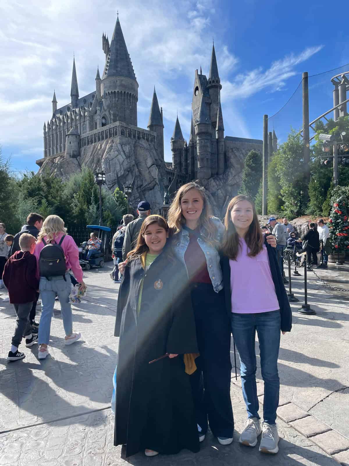 An image of a mother and daughters in front of the Hogwarts castle in Harry Potter World.